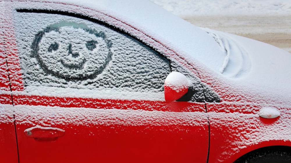 Glad gubbe ritad på en snöig bilruta
