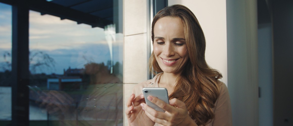Kvinna som ler mot en mobil